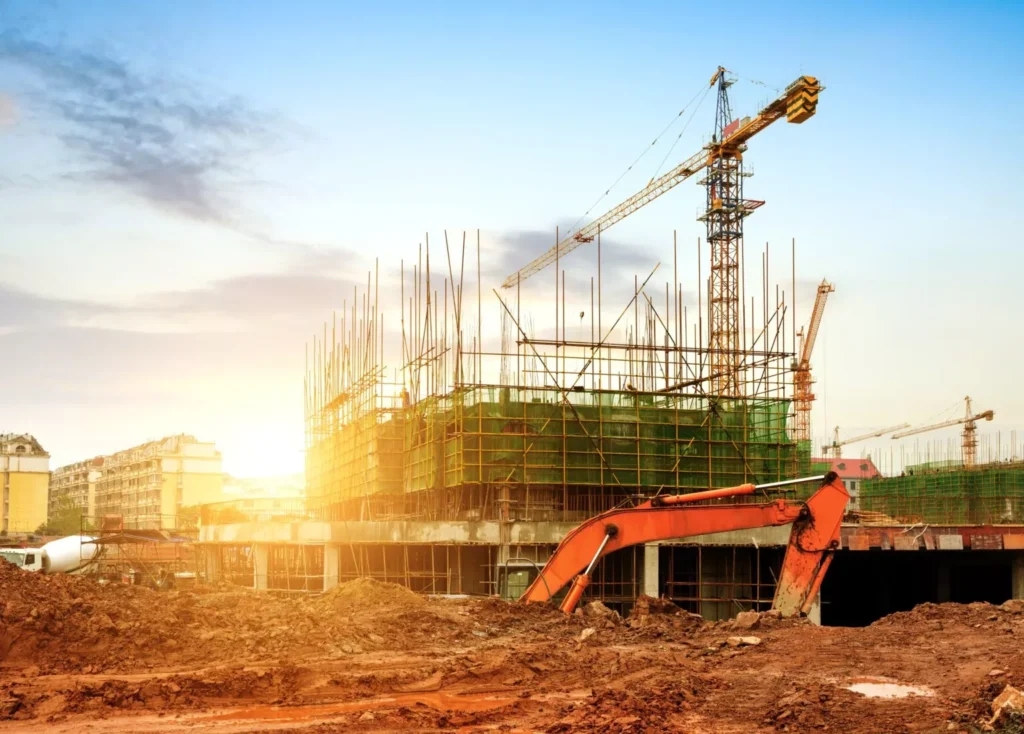 A bustling construction site featuring a towering crane, scaffolding, and heavy machinery under a bright sky, showcasing comprehensive construction services.