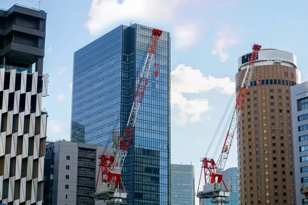 Construction cranes working on high-rise buildings in an urban area, representing masonry estimator services for large-scale construction projects.